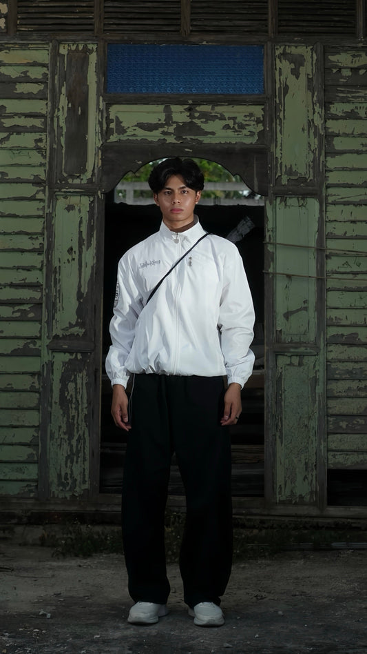Person wearing a white shirt and dark pants standing in front of a weathered wooden door.